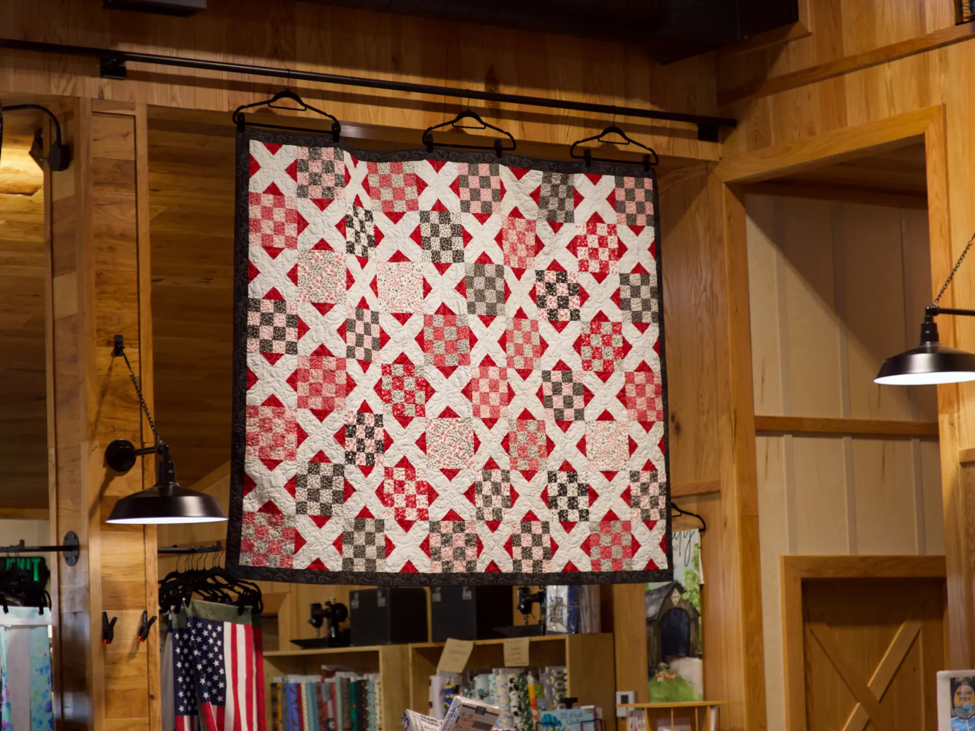 A completed quilt hanging from the ceiling in the All About Fabrics store